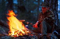 Man toasting bread on camp fire. Norway