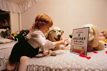 ic-04407 Child playing opticians with Golden retriever wearing glasses.