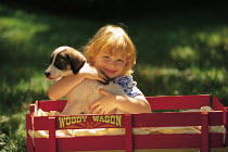 ic-04505 Child cuddling puppy in toy wagon.