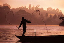 River fisherman throwing net from boat. Borneo, Malaysia