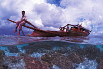 Bajau fisherman on traditional Lepa boat in shallow water over coral reef, split level, Pulau Gaya, Borneo, Malaysia