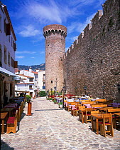 Street cafe tables in street next to ramparts at Tossa del Mar, Costa Brava, Catalunya, Spain