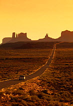 Car on road to Monument Valley at sunset, Navajo Tribal Park, Arizona, USA