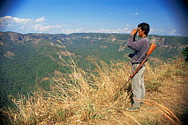 Forest guard ooking out across canyon, with tropical rainforest stretching below, Balpakram NP, Meghalaya, North East India