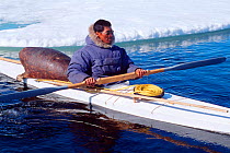 Inuit hunter in kayak with hunting gear including sealskin float, Canadian Arctic