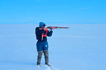 Inuit hunter take aim with gun, Canadian Arctic