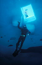 Diver under access hole that has been cut in the sea ice, Antarctica 1987