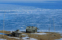 Fishing huts + men fishing through ice on Lake Baikal, Siberia, Russia