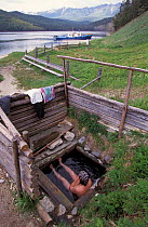 Fisherman bathing in wooden washtub beside Lake Baikal, Siberia, Russia