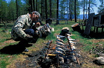 Man cooking fish over fire, Lake Baikal, Siberia, Russia