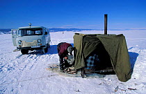 Fisherman with tent over ice hole on Lake Baikal, Siberia, Russia