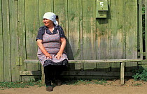 Woman sitting outside wooden house, Rougir village, Olhkon Is, Lake Baikal, Siberia, Russia