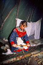 Sami woman in lavvu (tent) scraping reindeer hide, Karaskok, Samiland (Lapland), Finnmark, Northern Norway. 1997.