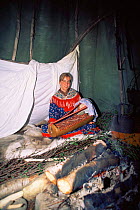 Sami woman in lavvu (tent) with traditional wooden baby cradle, Karaskok, Samiland (Lapland), Finnmark, Northern Norway. 1997.