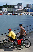 Cyclists looking at sea in Tenby, Pembrokeshire, Wales, UK.