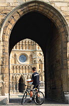Cyclist in archway of cathedral, Lincoln, England.