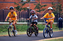 Three children cycling on path, Leicester, England