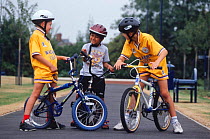 Three children standing with bikes on path, Leicester, England