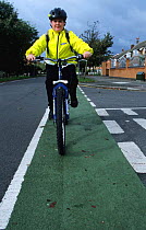 Boy cycling home from school in cycle land on road, UK