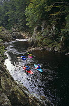 Canoeists navigate white water rapids, North Esk River, Scotland