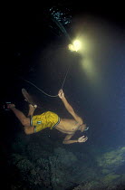 Seahorse fisherman at night swims below lantern on his boat, Handumon, Bohol Is, Philippines