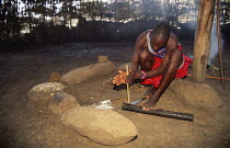 Maasai tribesman making fire by rubbing sticks together, Olonana village, Kenya