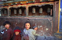 Children in front of prayer wheels, Phalla village, westbank of Kali Gandanki, Mustang, Nepal. November 2004