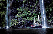 Boat at waterfall Milford Sound Fiordland NP South Is New Zealand