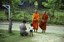 Buddhist monks pray with woman and child, Salakam, E-sarn, Thailand