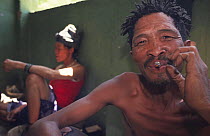 San bushmen family at home smoking cigarette, Kalahari desert, Namibia 2005