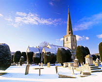 Church and churchyard with Yew trees in snow, Painswick, Cotswolds, Gloucestershire, UK.