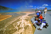Tourists on boardwalk looking at thermophile mats, formed by algae, bacteria and other heat loving micro-organisms, Black Sand Basin, Yellowstone