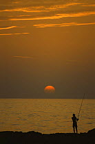 Angler with rod silhouetted at sunset, Italy