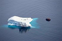 Tourists in dinghy watching Crabeater seals on iceberg, Antarctica.