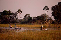 Tourists wildlife watching in Mokoro boats, Eagle Island Camp, Okavango delta, Botswana