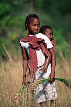 Girl carrying child collecting plants, Maputo Elephant reserve, Mozambique