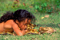 Child watches Roccoco toad {Bufo paracnemis} Cerrado, Brazil