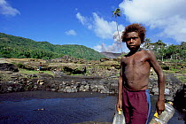 Local boy collecting water, Mount Yasur erupting in background, Tanna, Vanuatu