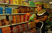 Cofan indian man with pet parrot shopping in Dureno community supermarket, Lago Agrio, Ecuador