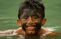 Boy with therapeutic mud mask swimming in sulphur lake, Machalilla NP, Ecuador 2004