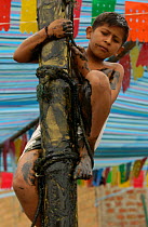 Child competing in greasy pole contest, Puerto Lopez, Ecuador 2004