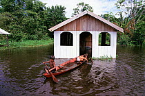 Children play in boat beside hut in flood, Mamiraua Ecol. Stn, Amazonas, Brazil