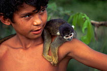 Boy with pet Blackish squirrel monkey {Saimiri vanzolinii} Amazonas, Brazil