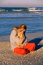 Girl hugs Golden retriever puppy on beach {Canis familiaris} Florida, USA. Model released