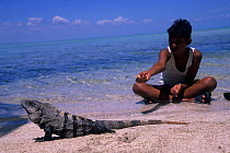 Boy next to Land iguana {Conolophus subcristatus} Sian Ka'an Biosphere Reserve, Mexico