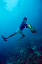 Hookah diver collects fish stunned by homemade bomb on coral reef, Philippines.