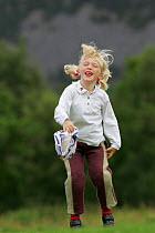 Young girl playing in summer meadow, Cairngorms National Park, Scotland, UK. Model released.