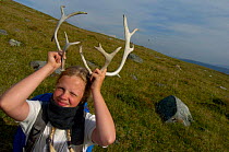 Child playing with antlers, Vindelfjallen Nature Reserve, Lapland, Sweden.