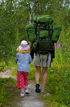 Parent and child rear view hiking in Vindelfjallen Nature Reserve, Lapland, Sweden.