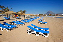 El Arenal, Tourist beach with sun loungers and umbrellas, Javea, Spain.